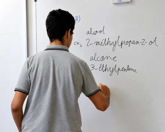 Élève qui écrit au tableau blanc pendant un cours particulier de sciences
