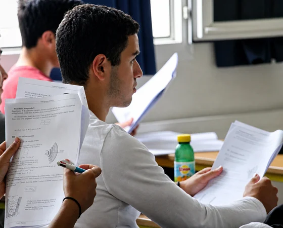 Candidats de terminale qui feuillettent leurs sujets dans une salle d'examen
